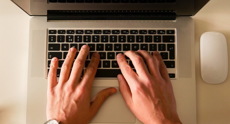 Bureau avec un MAC, ordinateur portable et des mains
