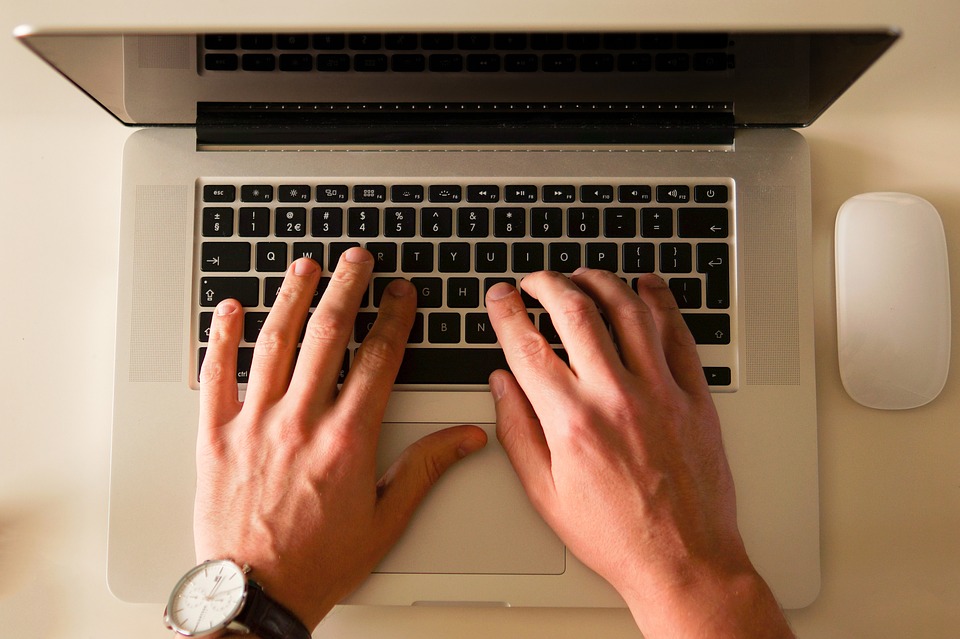 Bureau avec un MAC, ordinateur portable et des mains